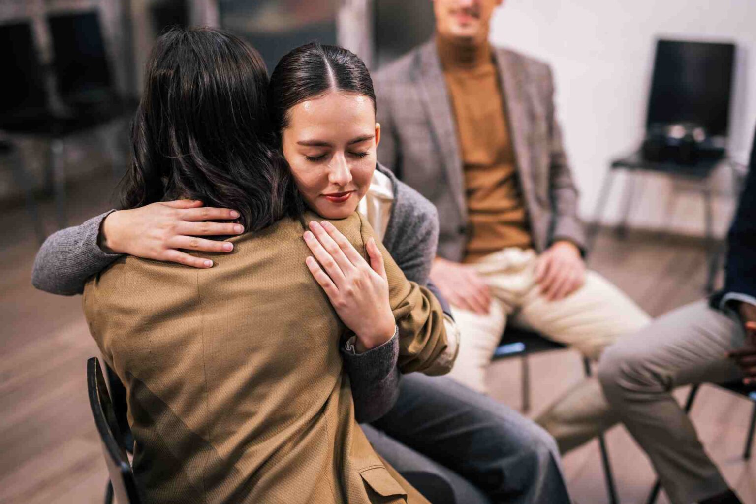 Two women hugging during a group therapy session for addiction treatment support