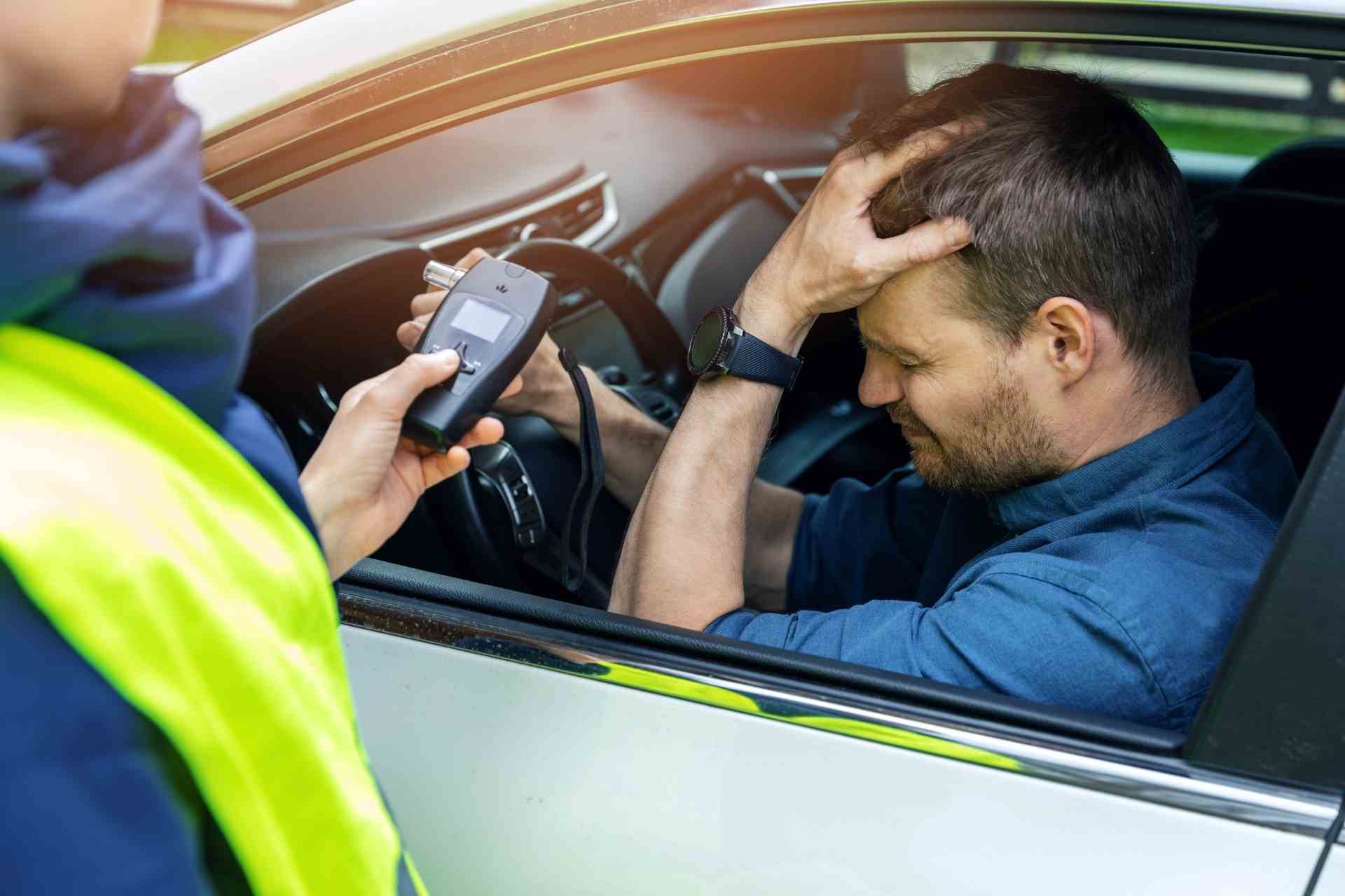 Police officer conducting a roadside sobriety check with a distressed driver seated inside a car